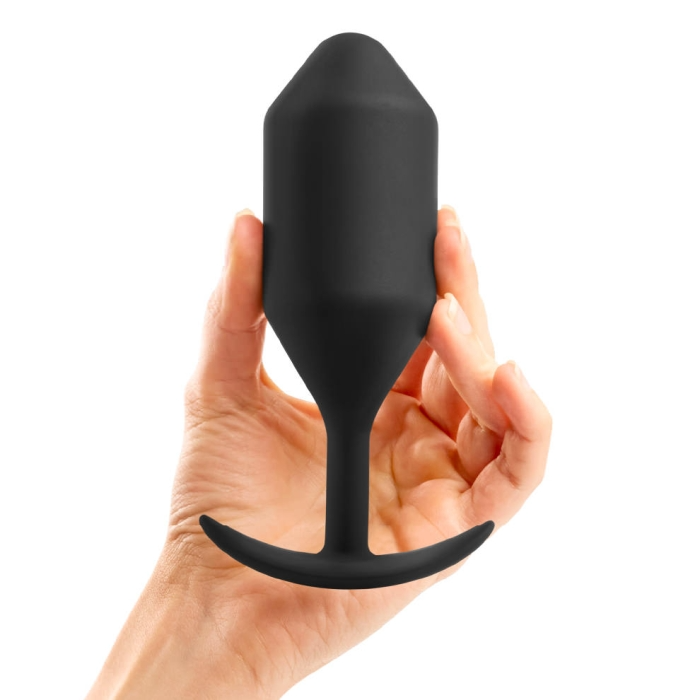 A black weighted silicone anal plug held in a hand.