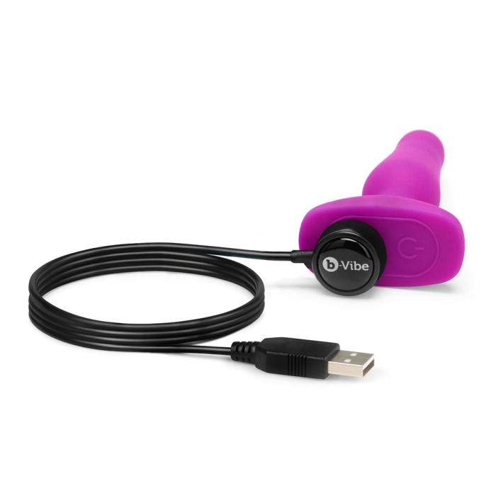 Fuchsia b-Vibe Novice vibrating anal plug with USB charging cable.