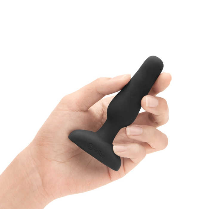 Black silicone vibrating anal plug held in a hand.