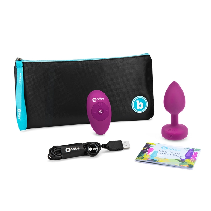 Fuchsia b-Vibe Vibrating Jewel Anal Plug set with remote, charging cable, and guide.