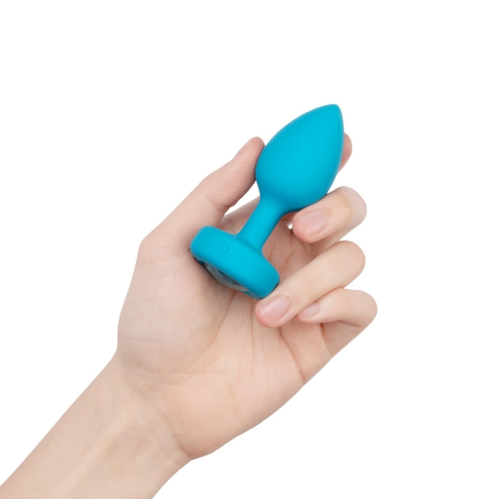 A teal vibrating anal plug held in a hand.