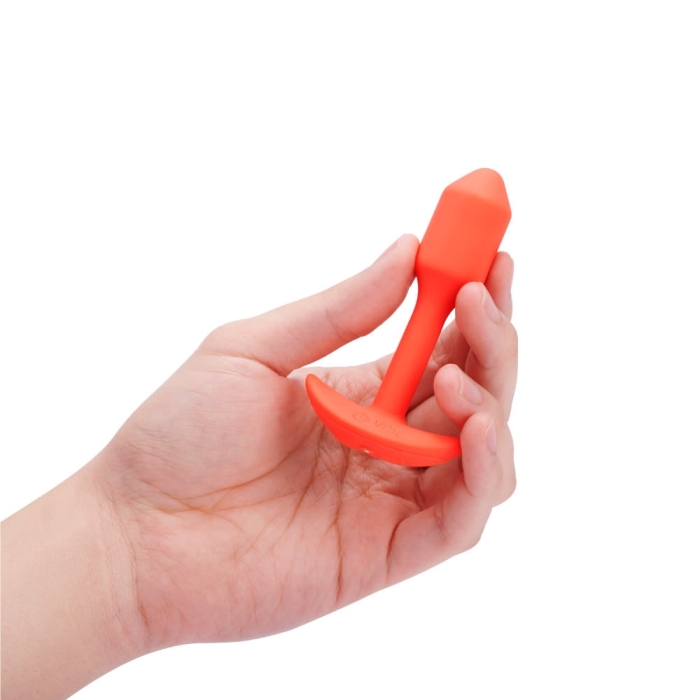 Orange silicone vibrating snug plug held in a hand.