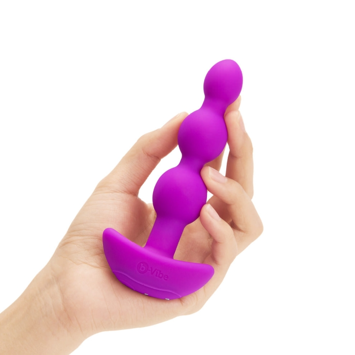 Fuchsia silicone vibrating anal beads held in a hand.