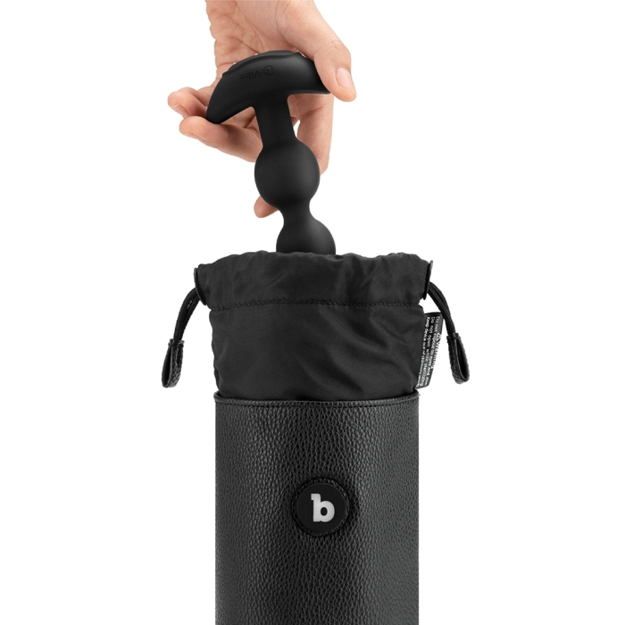 A hand holds a black sex toy above a black pouch inside a black leather case.