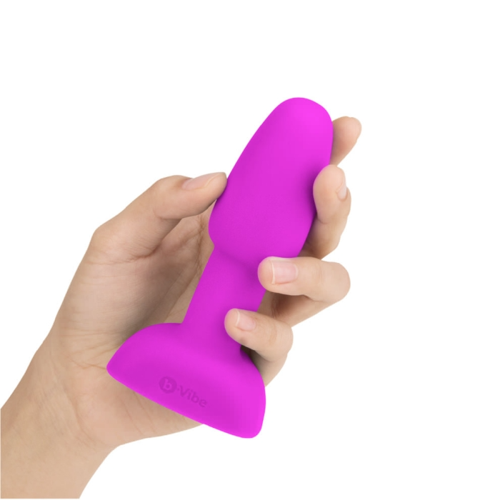 A fuchsia vibrating anal plug held in a hand.