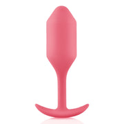 A coral weighted silicone anal plug with a flared base.
