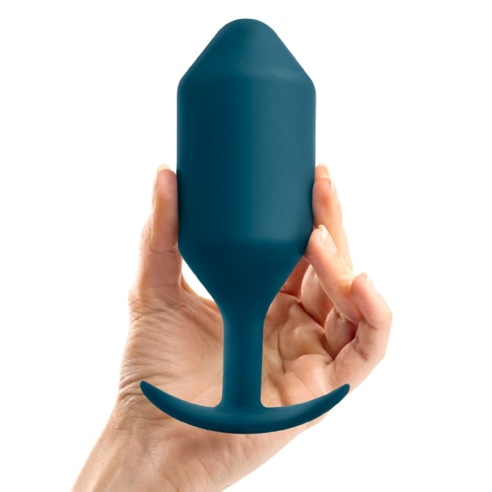 A hand holds a marine blue weighted silicone anal plug with a flared base.