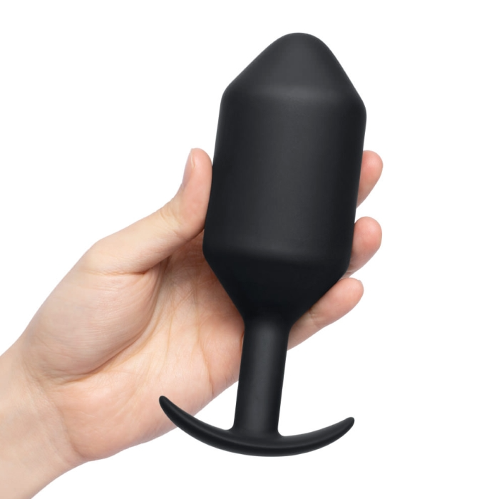 A black weighted silicone anal plug held in a hand.