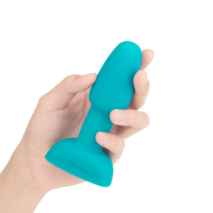 A teal vibrating anal plug with a flared base held in a hand.
