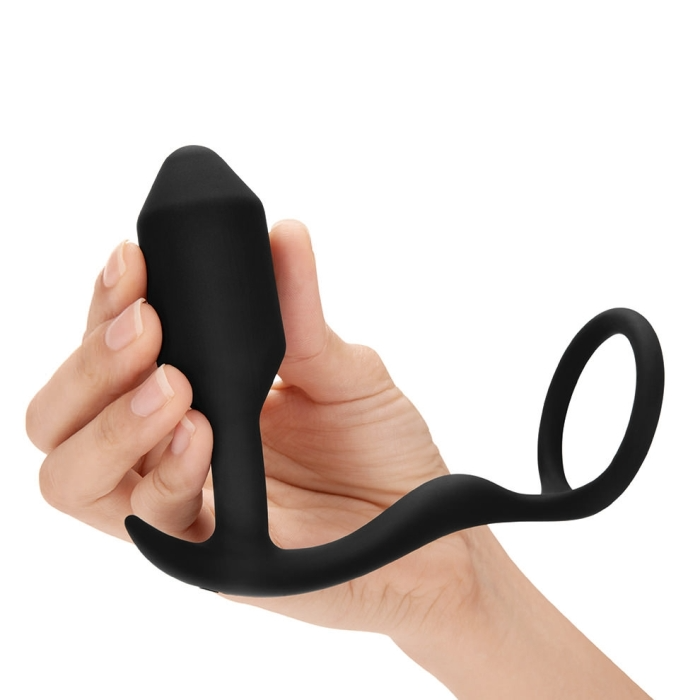 Black silicone weighted anal plug and cock ring held in a hand.