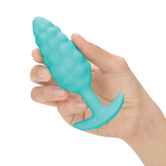 A teal, textured, vibrating anal plug held in a hand.