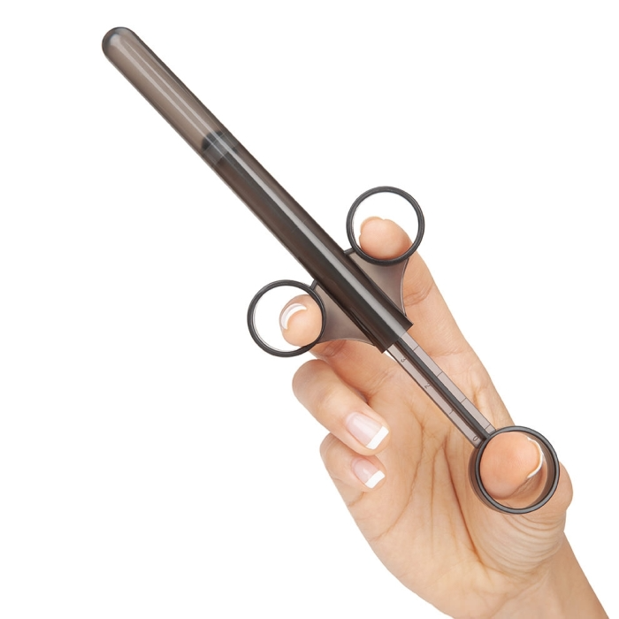 A hand holds a dark grey lube applicator with finger loops.