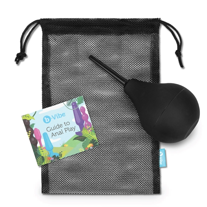 A black enema bulb with a nozzle sits on a mesh bag next to a small booklet.