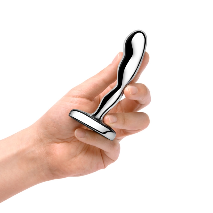 A hand holds a curved, weighted stainless steel anal plug.