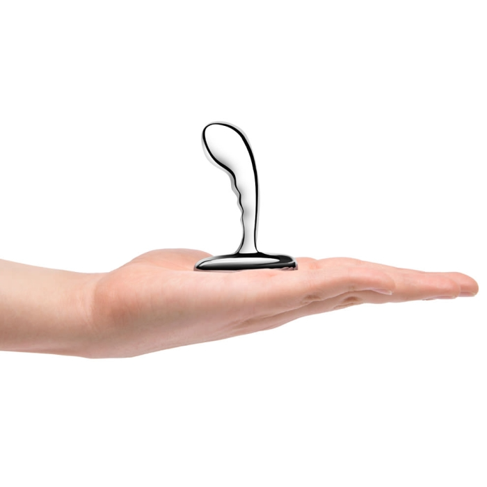 A silver prostate plug rests on an open palm.