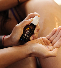 A hand dispenses Foria Intimacy Awaken Arousal Oil into another palm.