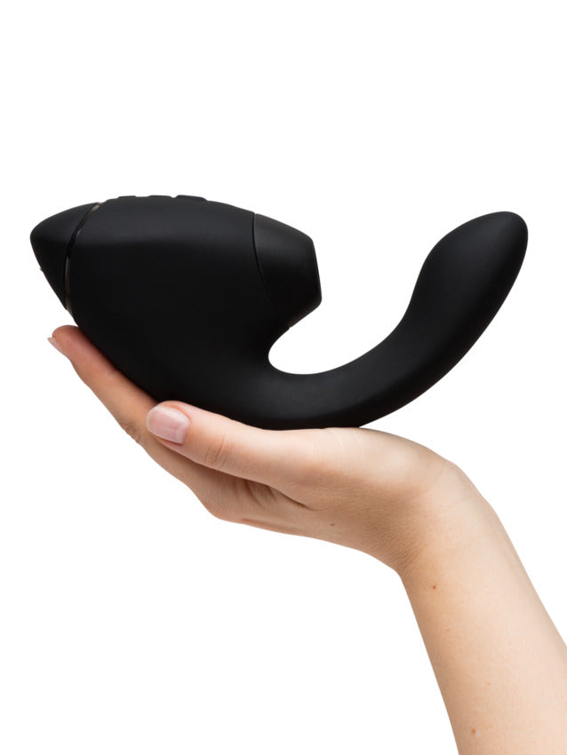 A black dual stimulator held in a hand.