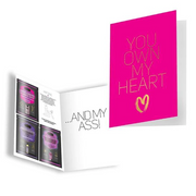 A pink card with gold text saying "YOU OWN MY HEART" and a booklet with lube and massage oil samples.