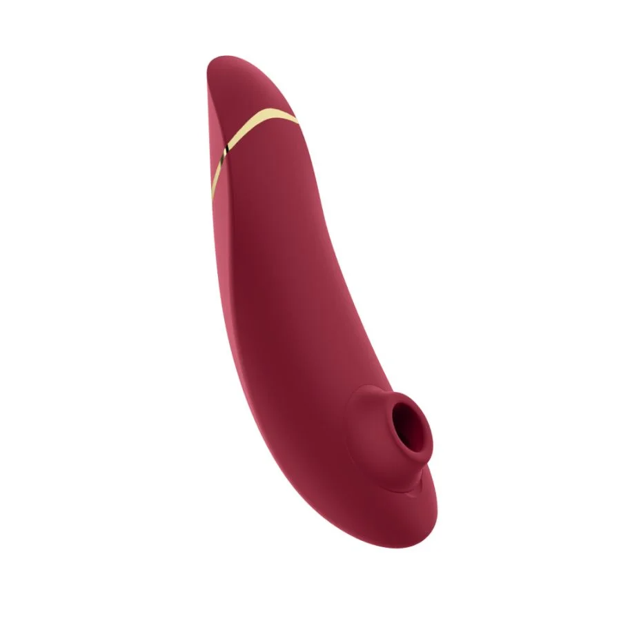A curved, deep red clitoral vibrator with a gold accent.
