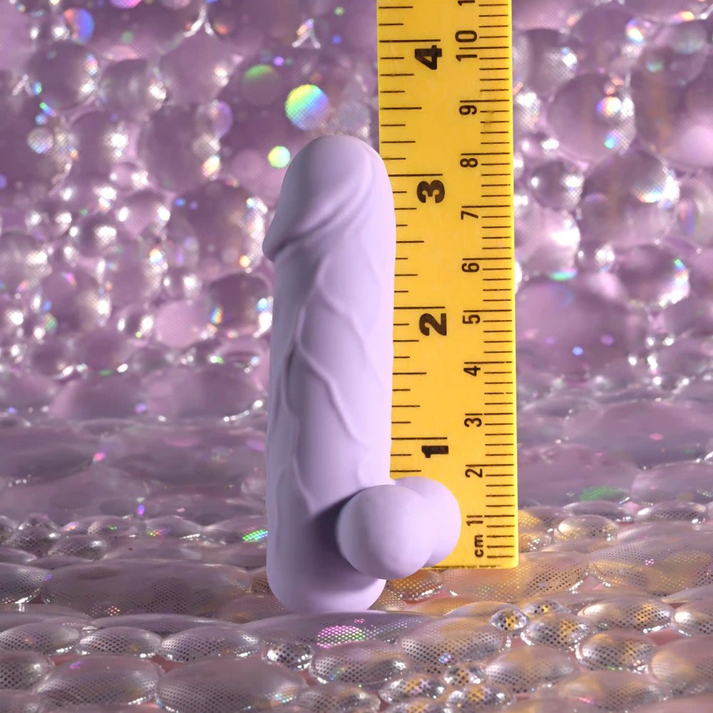 A purple silicone vibrator with a textured shaft and a bulbous base, measured against a ruler.