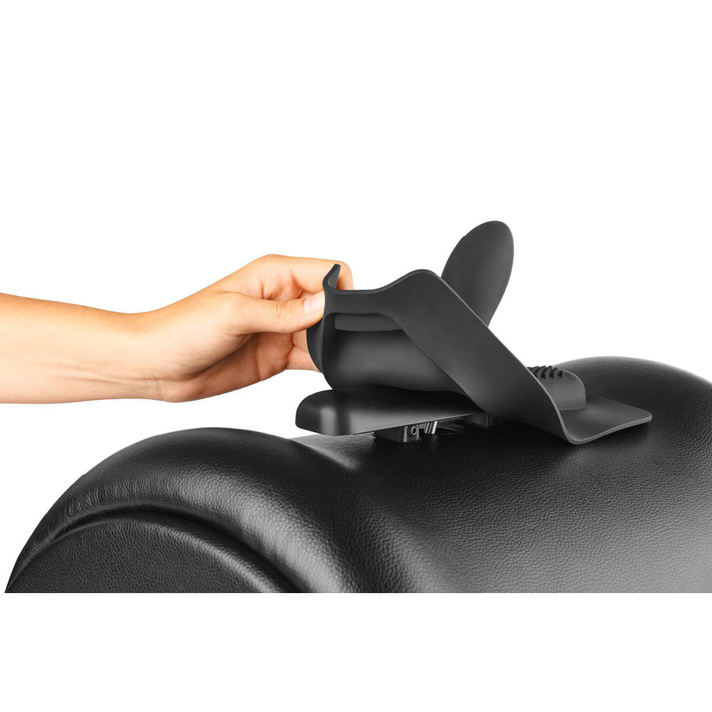 A hand holds a black silicone attachment over a black textured surface.