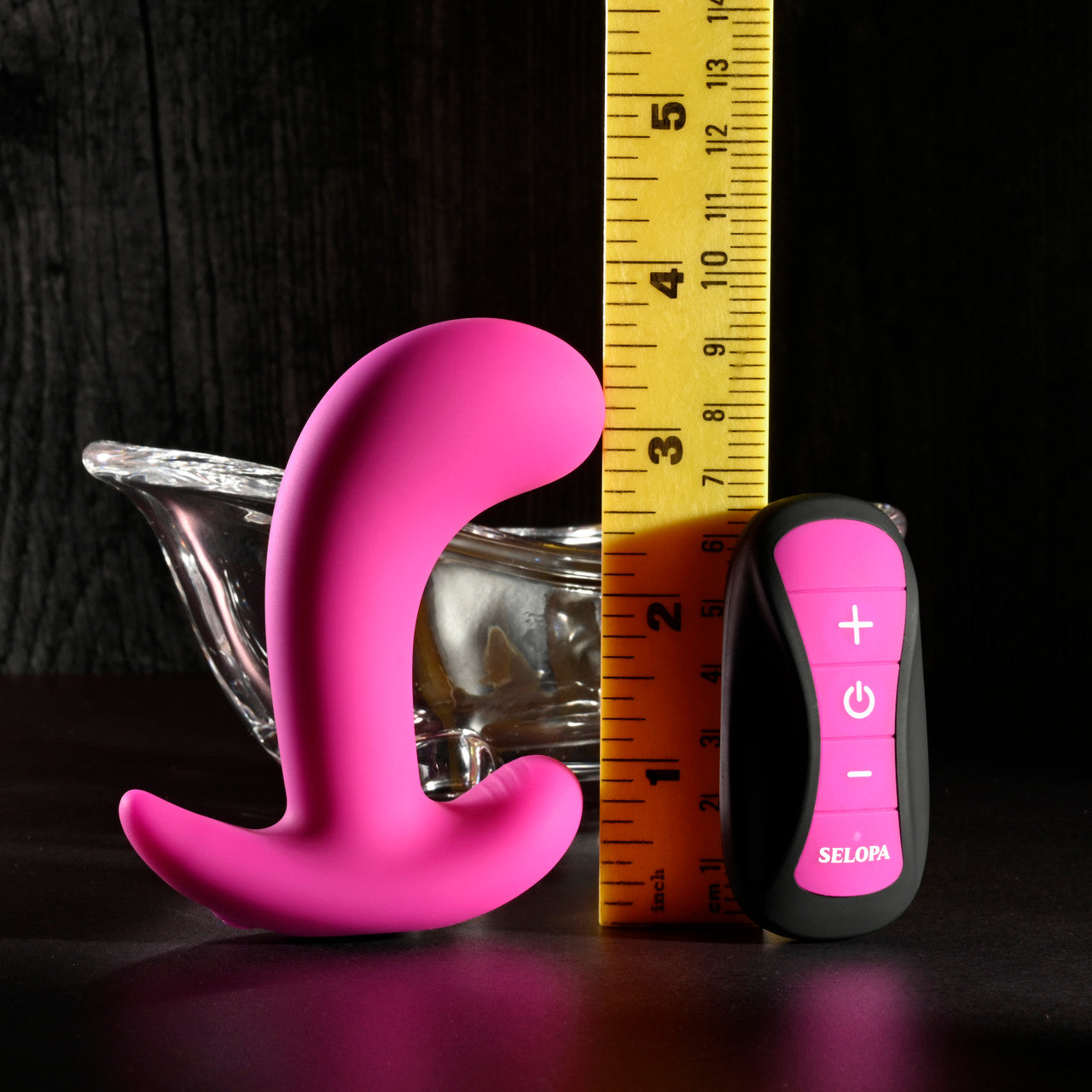 Pink silicone prostate massager with remote control and ruler for scale.