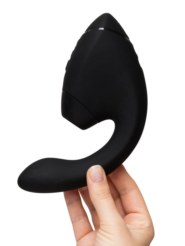 A black dual stimulator with a curved design, held by a hand.