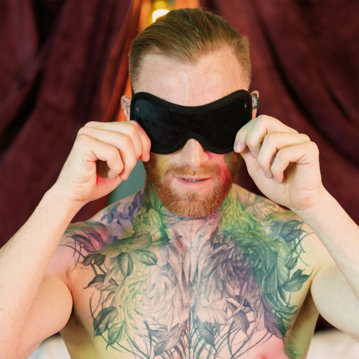 Man wearing a black blindfold over his eyes, with extensive chest tattoos.