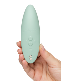 A sage green We-Vibe Melt 2 clitoral stimulator held in a hand.
