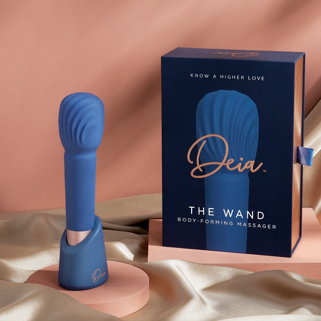 A blue Deia wand massager with a charging stand and its box.