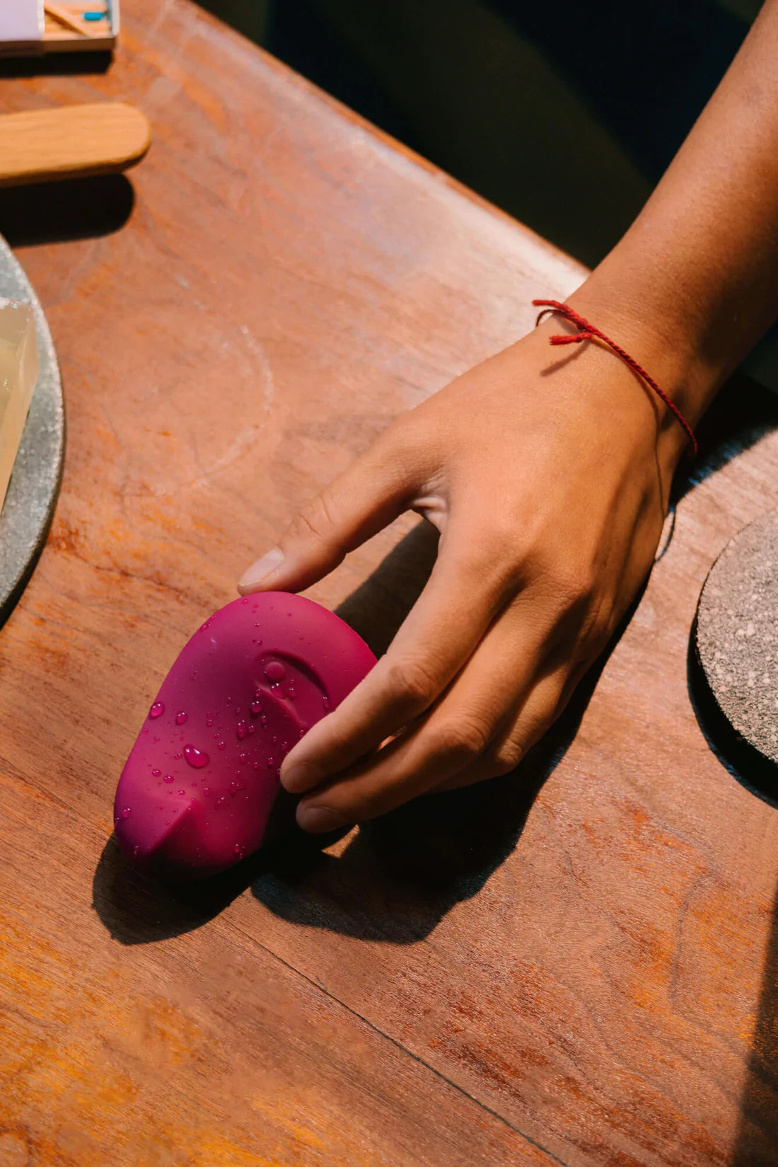 A plum-colored flexible silicone vibrator with water droplets on it.