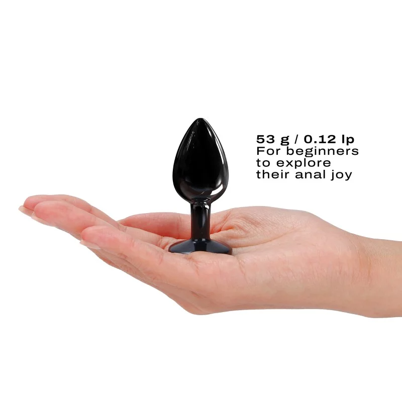 Black metal anal plug with jewel base held in a hand.