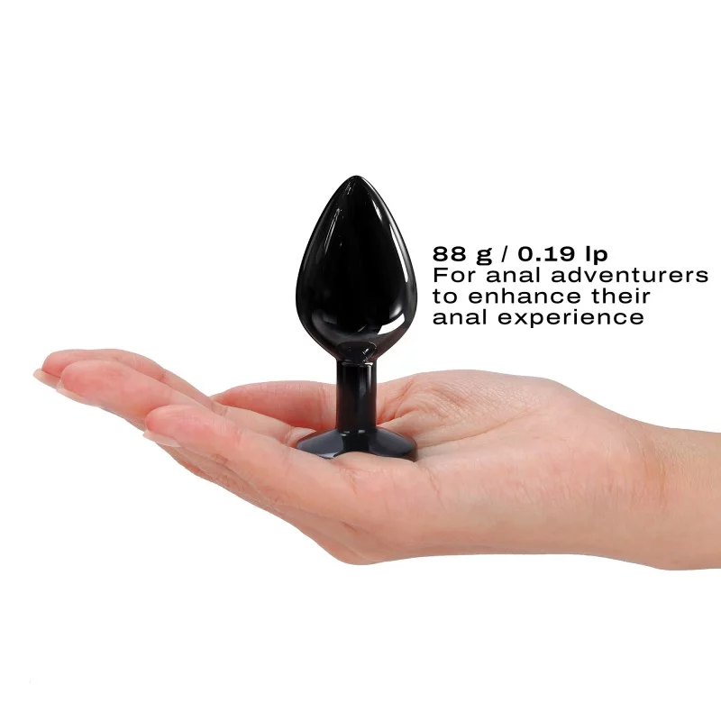 Black metal anal plug with a diamond base held in a hand.