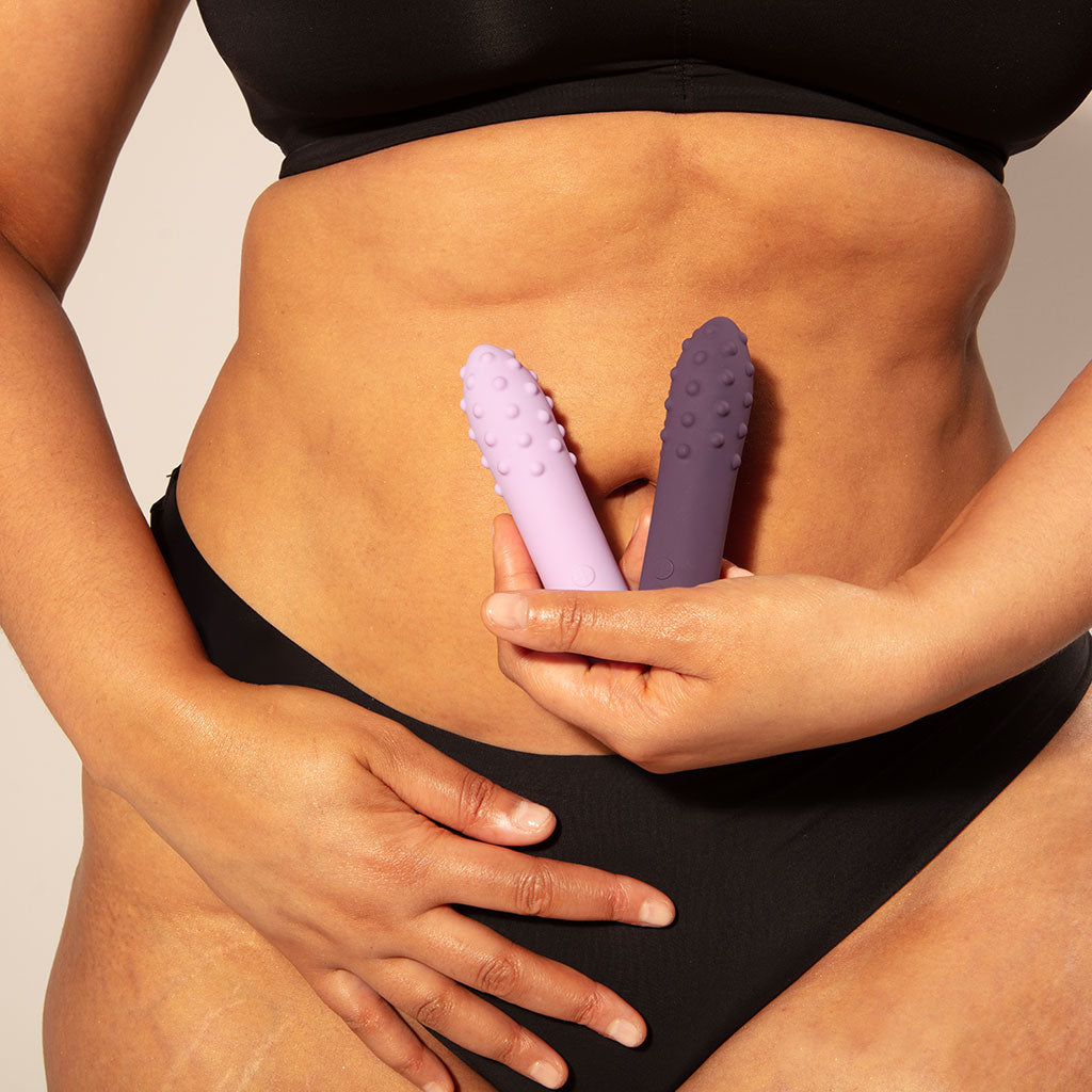 Lilac and purple silicone vibrators with textured tips held by hands.