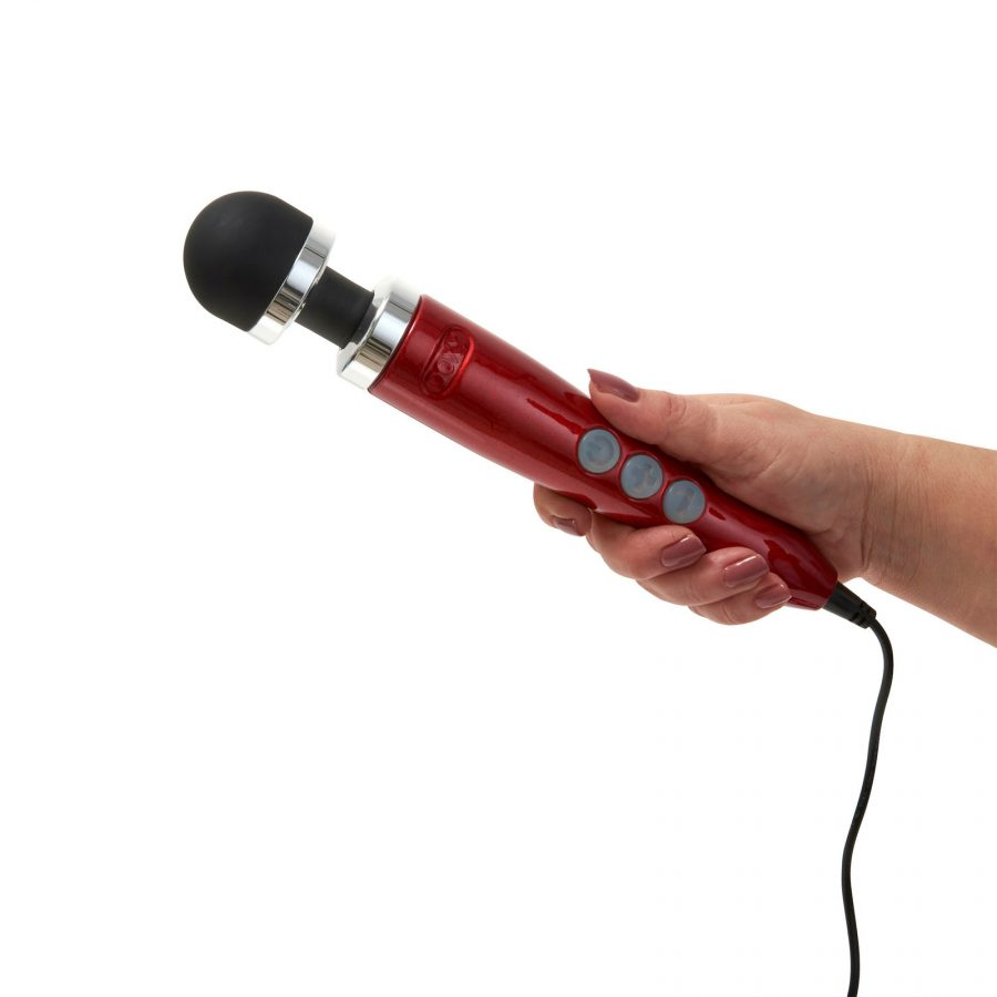 Red wand massager with a black silicone head held in a hand.