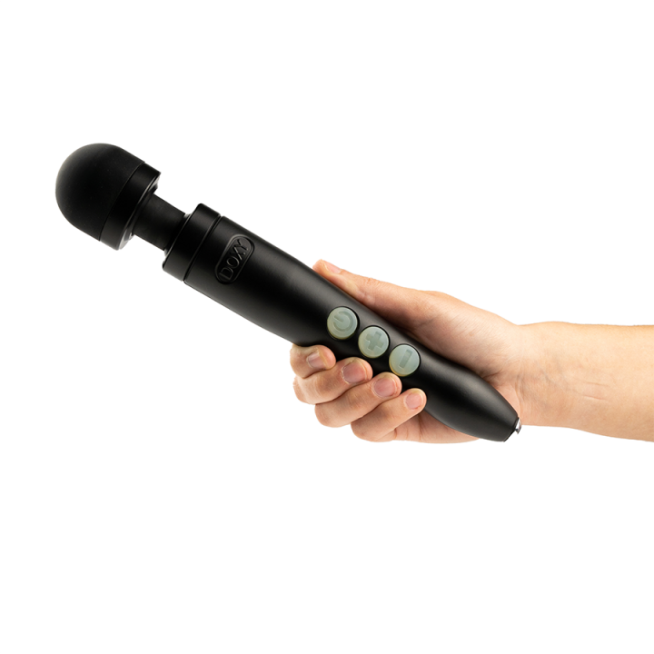 A black Doxy wand massager with three buttons held in a hand.