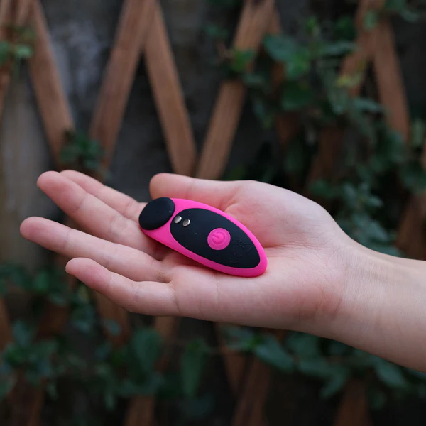 A pink and black remote-controlled vibrating panty toy rests in an open palm.