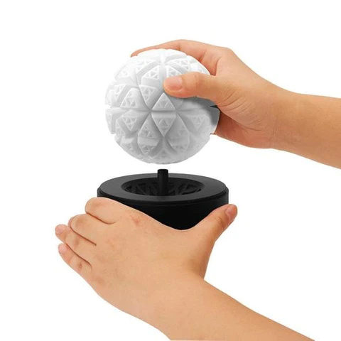 White textured masturbator sleeve being held above a black stand.