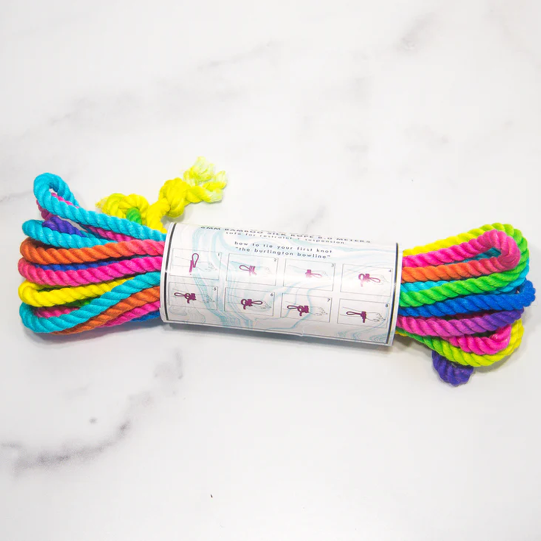 A rainbow-colored bamboo silk rope coiled on a white marble surface.