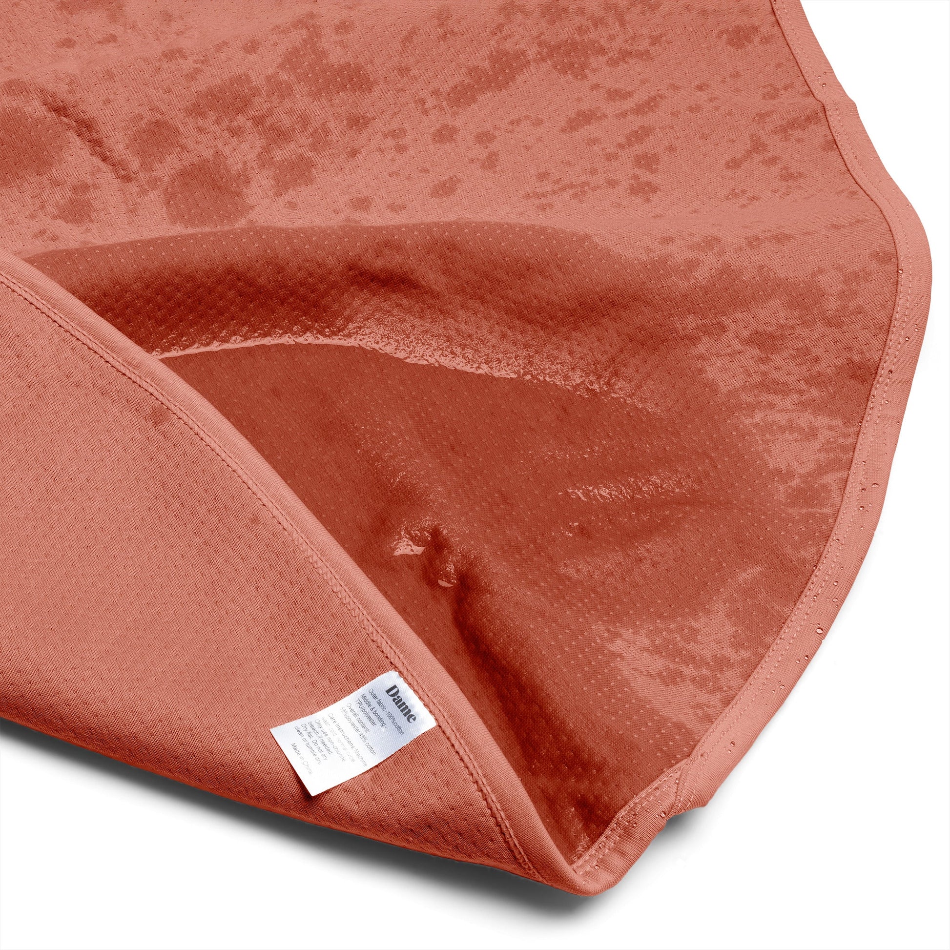 Copper waterproof blanket with a textured surface and a visible care tag.
