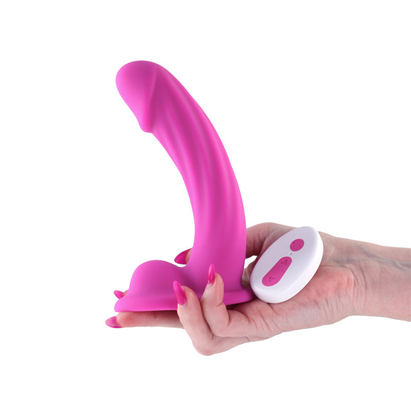 Pink curved dildo with a white wireless remote held in a hand.