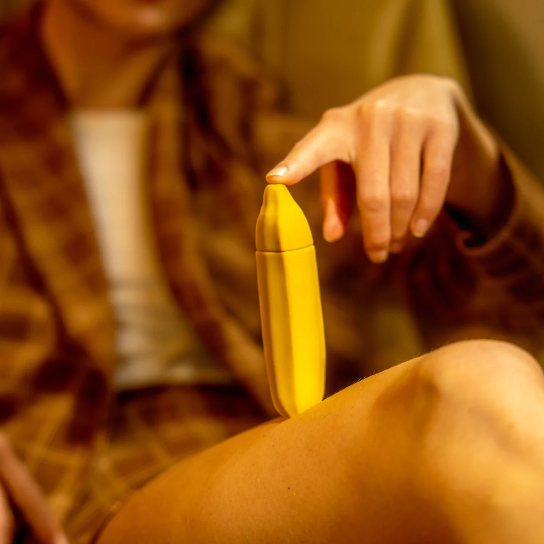 Yellow banana-shaped vibrator held by a person's finger.