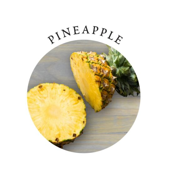 A halved pineapple and a pineapple slice on a wooden surface.