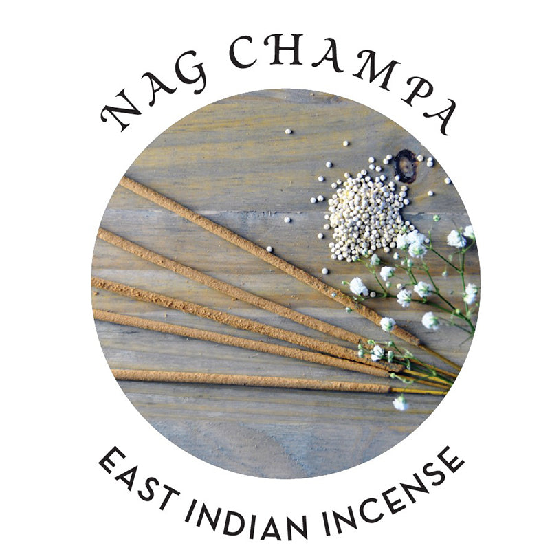 Nag Champa incense sticks and white flowers on a wooden surface.