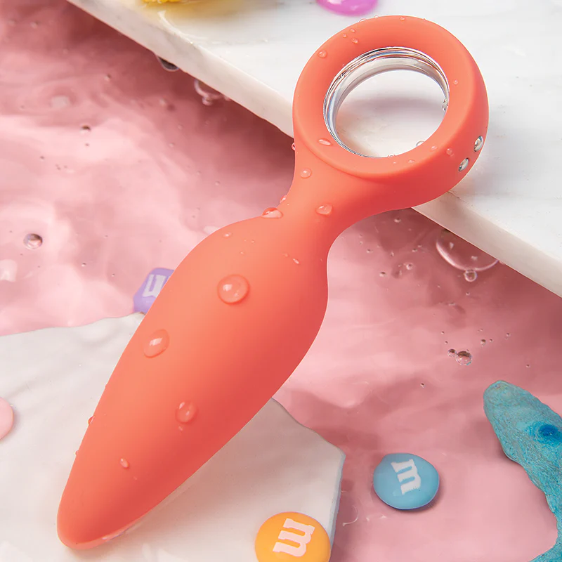 Orange vibrating silicone butt plug with a ring handle and water droplets.