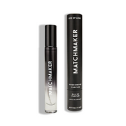A black and clear rollerball bottle of Matchmaker Pheromone Parfum next to its black cylindrical packaging.