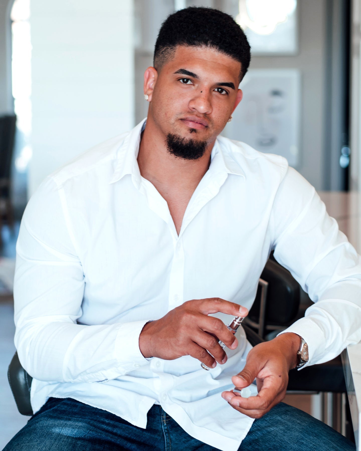 Man in white shirt applying cologne.