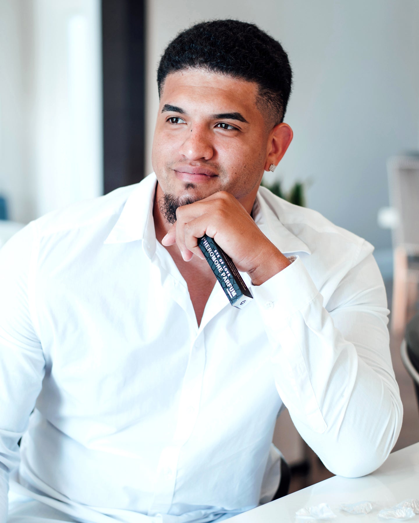 Man in white shirt holding a bottle of Confidence Pheromone Cologne.