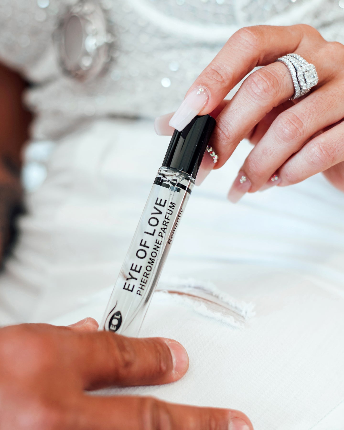 A woman's hand holds a rollerball bottle of "Eye of Love" pheromone parfum.