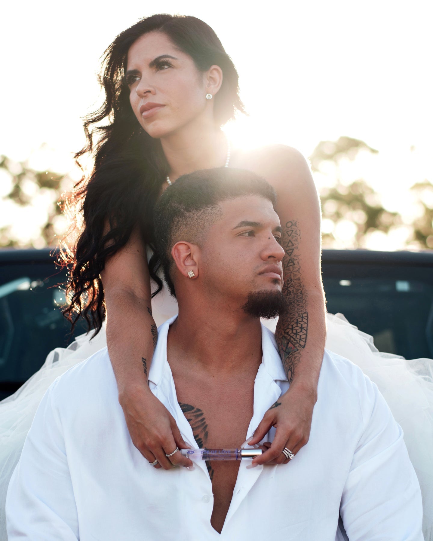 A woman's hands hold a clear tube of pheromone perfume against a man's chest.